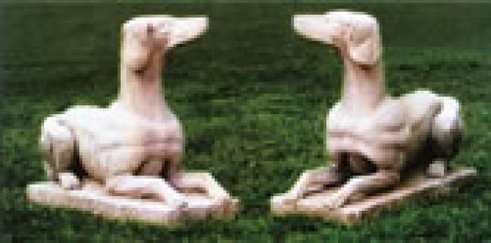 Two stone dogs sitting on the grass